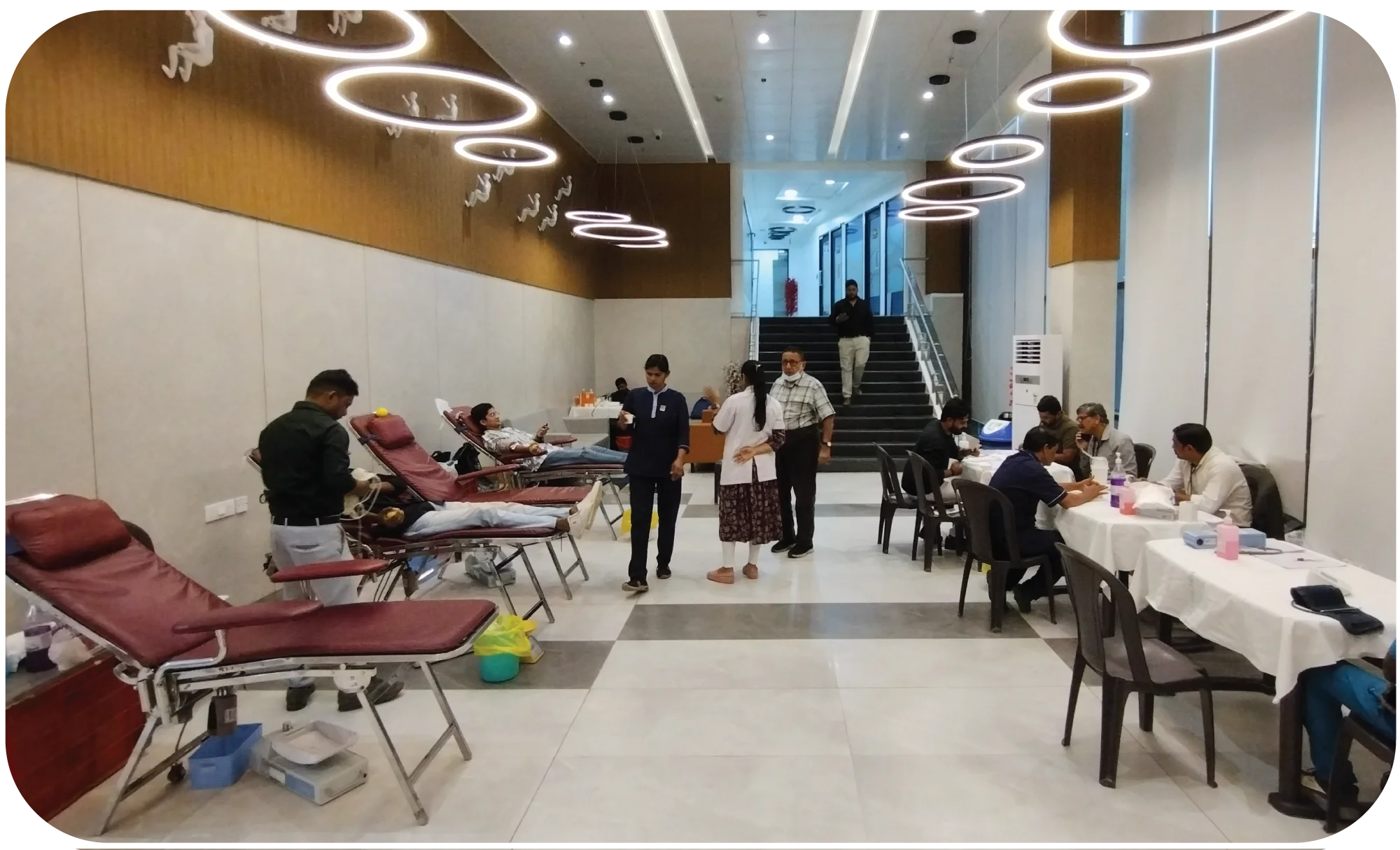 Blood donation camp setup with multiple beds and volunteers assisting donors